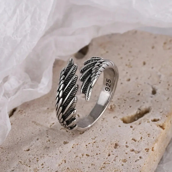 Silver ring with feather design on a textured surface