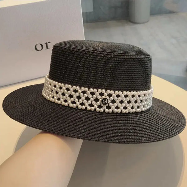Black straw hat with pearl band on a neutral background