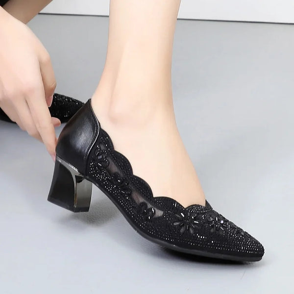 Black high-heeled shoes with floral patterns on a light gray background