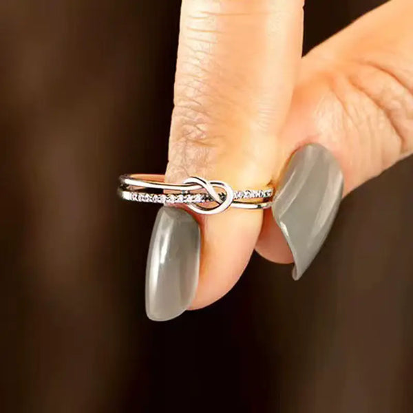 Close-up of a hand wearing a silver ring with a unique design on a dark background