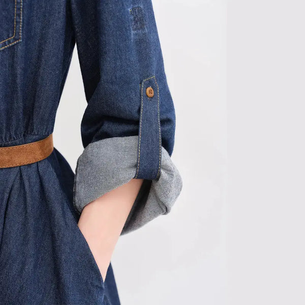 Denim dress with rolled-up sleeves and a brown belt on a light gray background