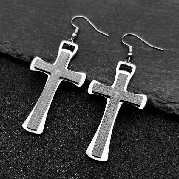 Silver cross earrings on a dark stone surface
