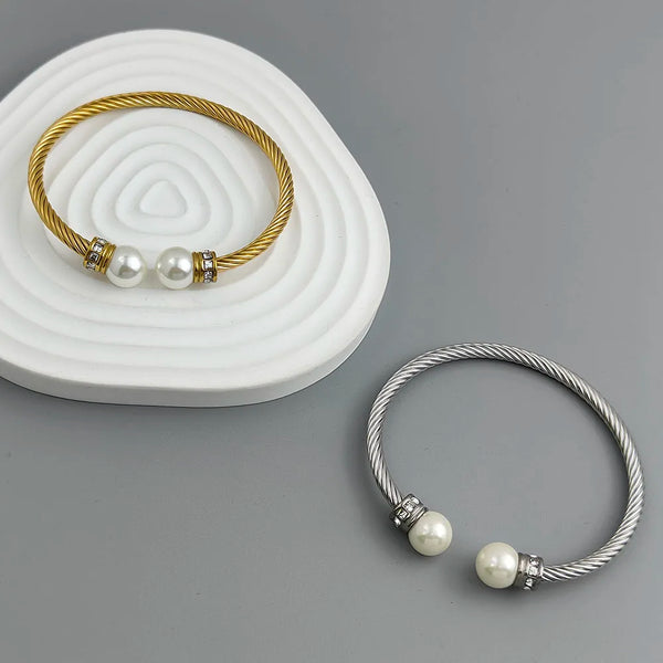 Two pearl-branded bracelets, one gold and one silver, on a gray background.