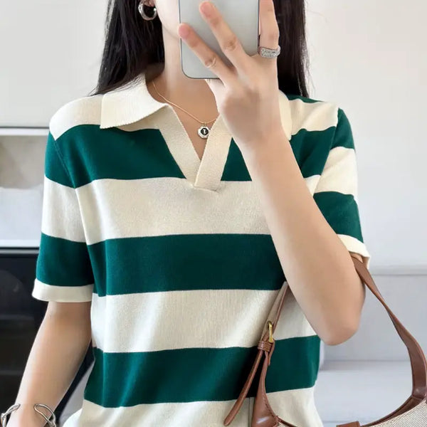 Person wearing a green and white striped shirt holding a phone.