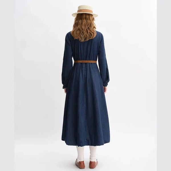 Person wearing a long navy dress with a brown belt on a white background