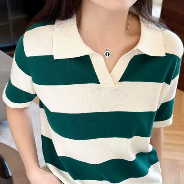 Person wearing a green and white striped polo shirt indoors.