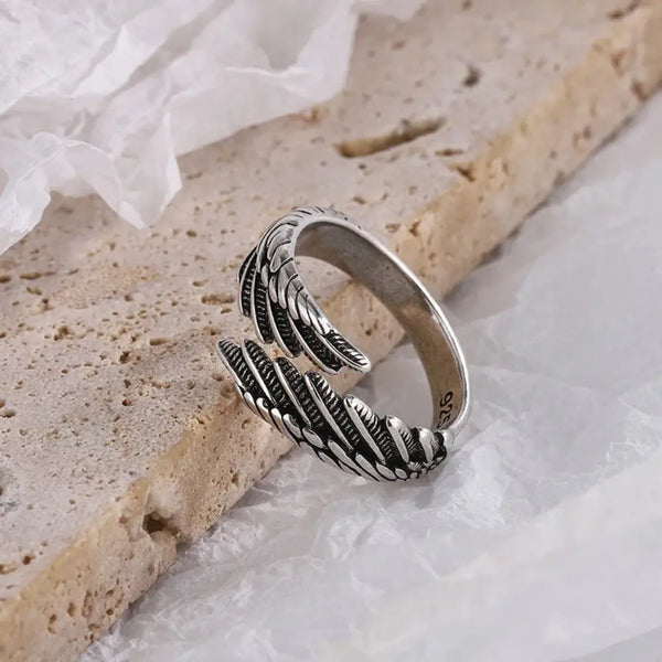 Silver ring with feather design on a textured surface