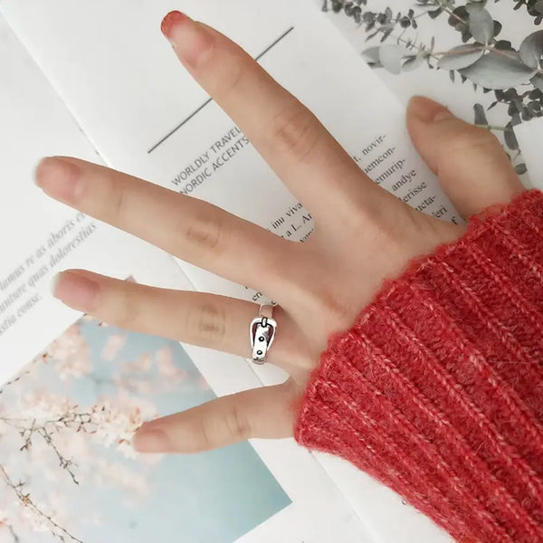 Hand wearing a silver ring with a red sleeve on a blurred background