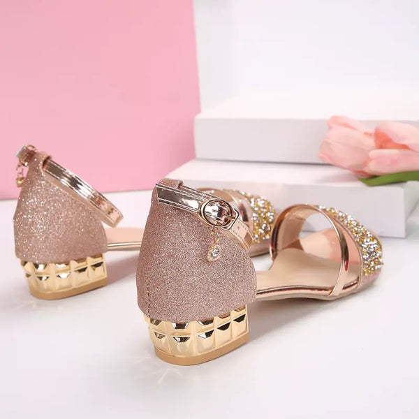 Rose gold glittery high heels with rhinestone embellishments on a white background.