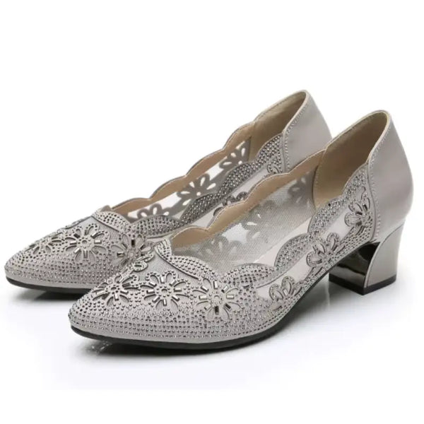 Silver high-heeled shoes with intricate cut-out designs on a white background