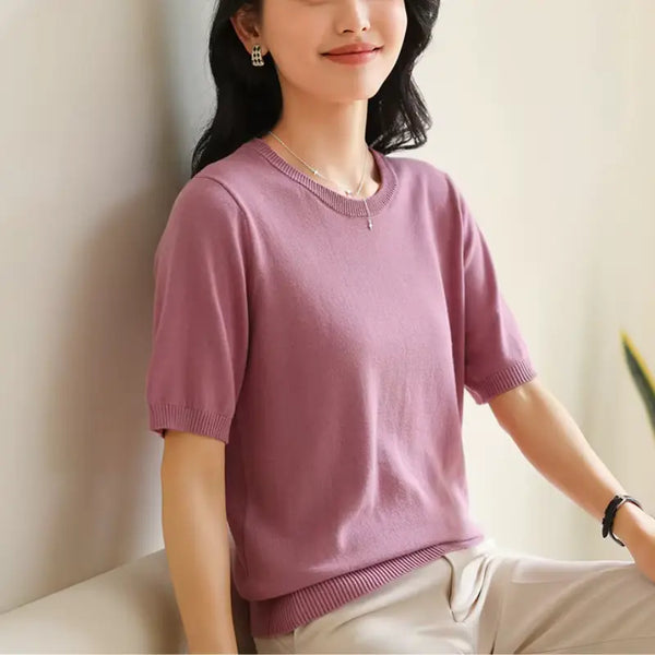 Woman wearing a pink sweater against a plain background
