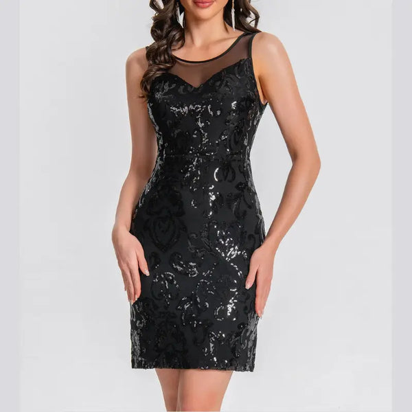 Woman wearing a silver one-shoulder dress with fringe details against a white wall.