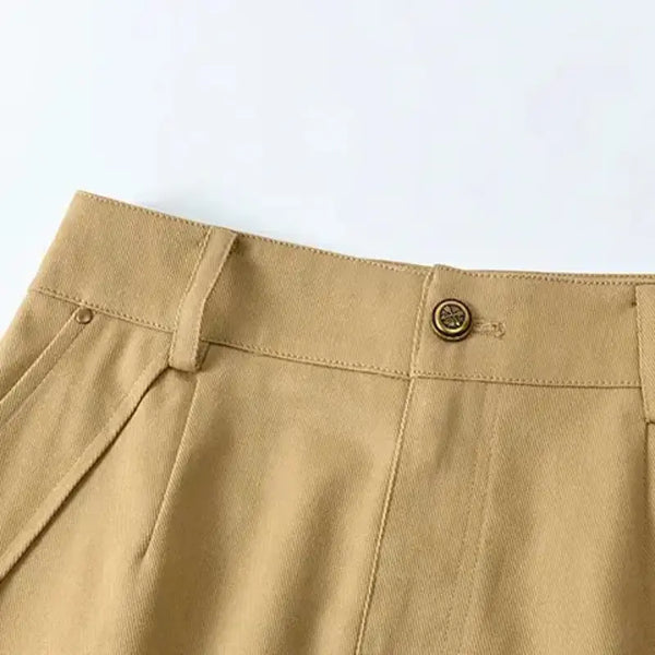 Close-up of beige pants with a button on a light blue background