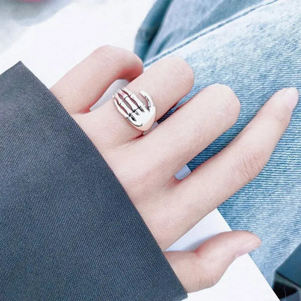 Hand wearing a silver ring with a blurred background