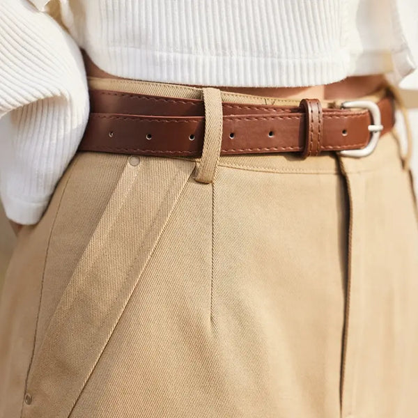 Close-up of beige pants with a brown belt and white shirt.