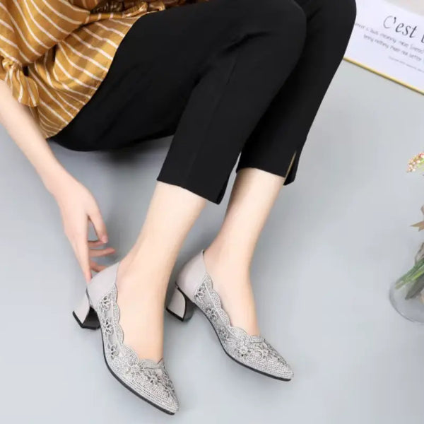 Person wearing gray pointed-toe shoes with a patterned design on a light gray background
