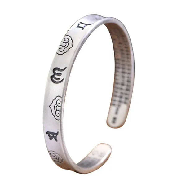 Silver bracelet with engraved symbols on a white background