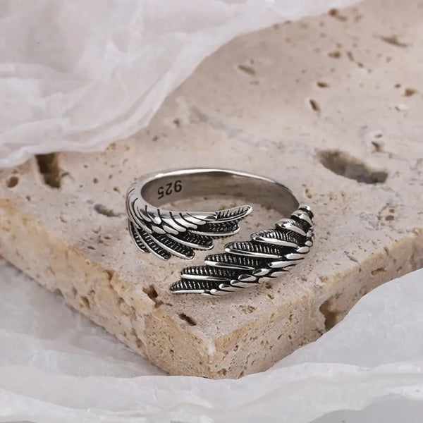 Silver feathered ring on a textured stone surface