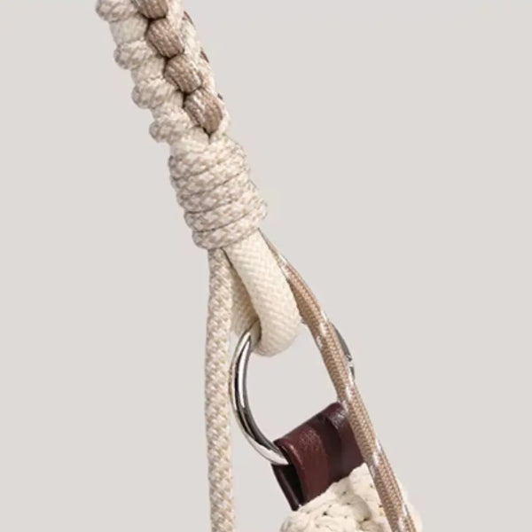 Close-up of a beige braided rope with a metal ring and brown leather strap on a light gray background
