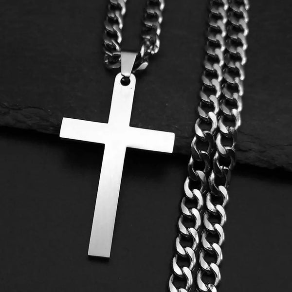 Silver cross pendant on a chain against a dark background