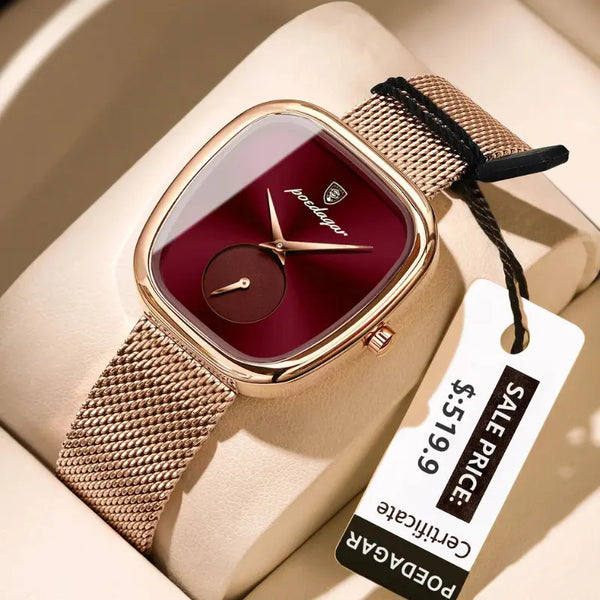 Gold watch with a red face on a beige surface, accompanied by a price tag.