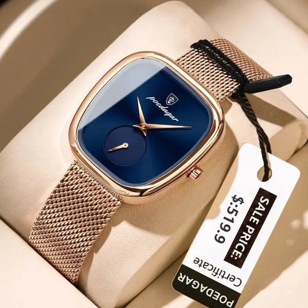 Gold watch with blue face and mesh band on a beige surface with a price tag.