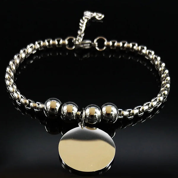 Silver beaded bracelet with a gold round pendant on a black background