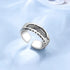 Silver ring with feather design on a light blue fabric background