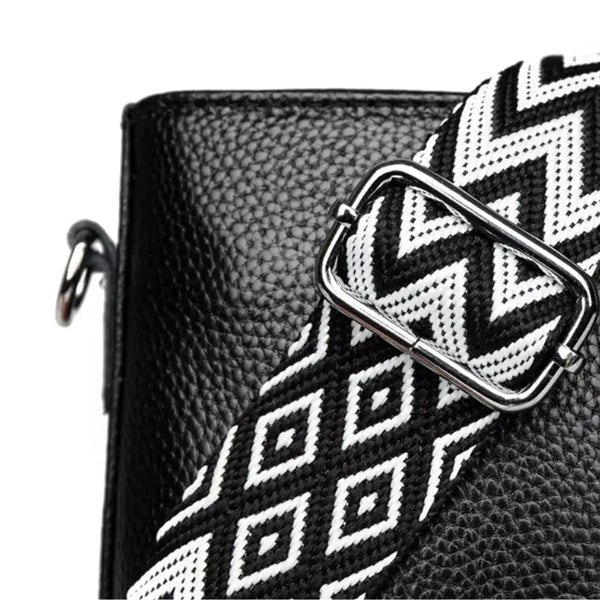 Black leather clutch with a white geometric patterned strap on a white background
