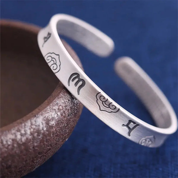 Silver bracelet with engraved symbols on a blue background
