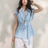Woman wearing a light blue sleeveless blouse with a tie waist against a plain background