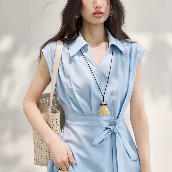 Woman wearing a light blue sleeveless dress with a neutral background
