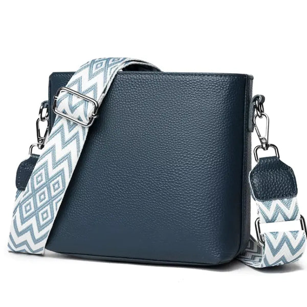 Blue leather handbag with a patterned strap on a white background