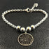 Bracelet with silver beads and a gold pentagram charm on a black textured background