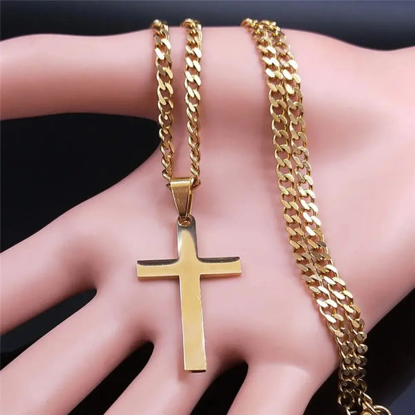 Gold cross pendant and chain on a hand against a dark background