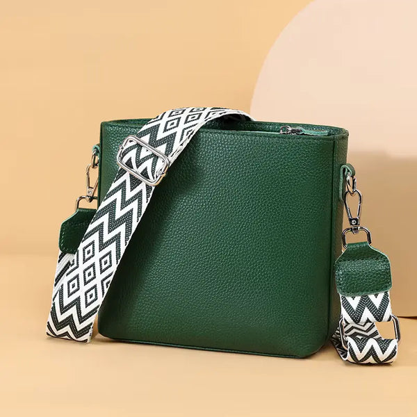 Green handbag with a patterned strap on a beige background