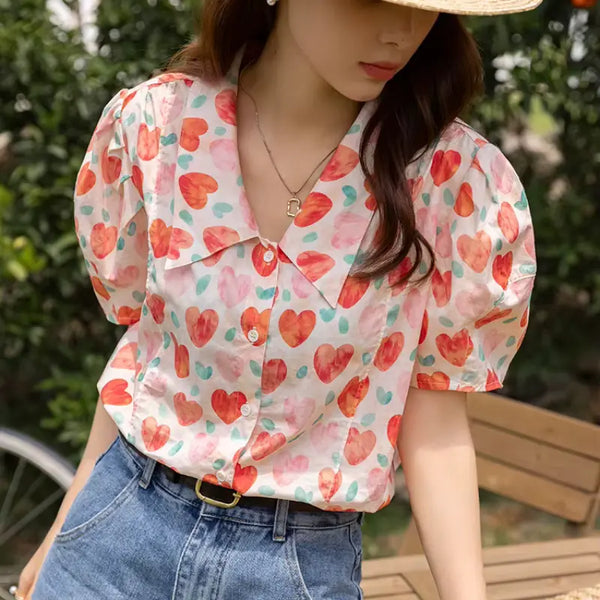 Woman wearing a heart-patterned blouse and straw hat outdoors