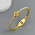 Gold bracelet with a floral clasp on a gray background