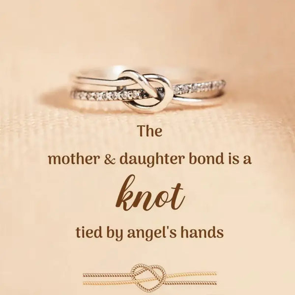 Silver ring with interlocking design on a beige background with text about mother-daughter bond.