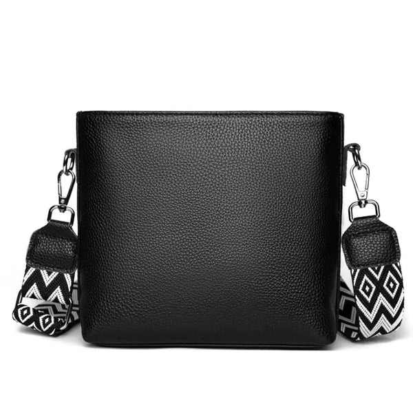 Black leather handbag with decorative tassels on a white background