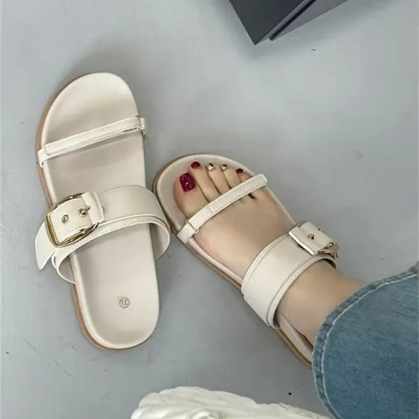 Beige sandals with a buckle on a light gray surface