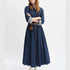 Woman wearing a long denim dress with a belt on a white background