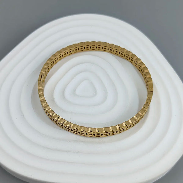 Gold bracelet on a white stone surface with a gray background