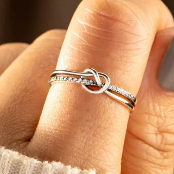 Silver ring with a knot design on a person's finger