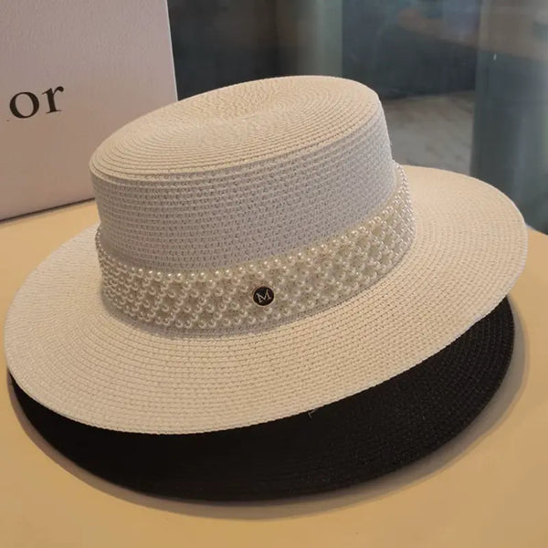 Beige straw hat with black band and decorative band on a beige surface