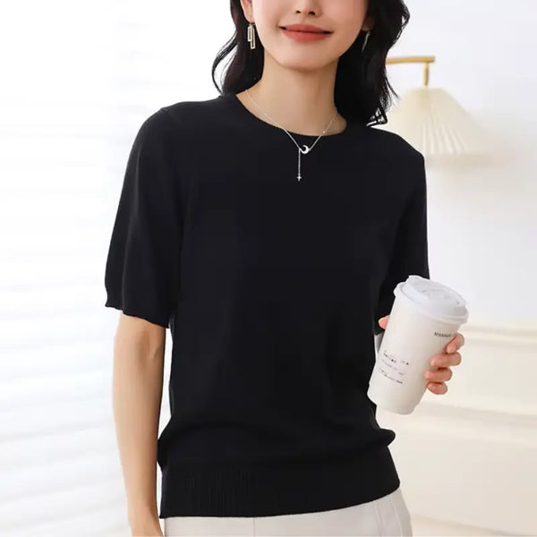 Person wearing a black sweater holding a white coffee cup against a light background