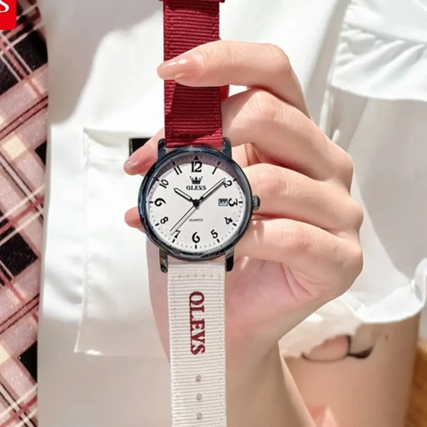 Hand holding a watch with a red strap featuring the brand 'OLEVS'.