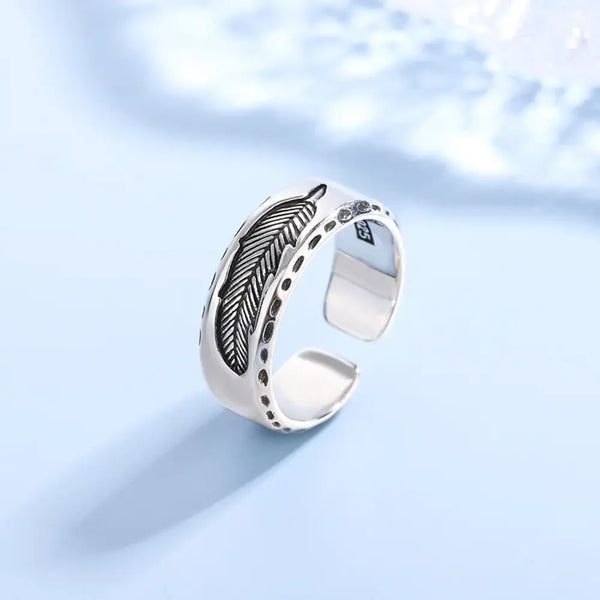 Silver ring with feather design on a light blue background