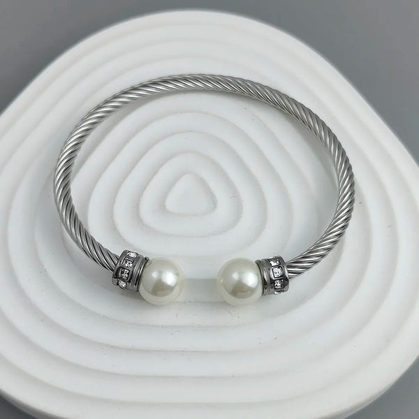 Silver cable bracelet with pearl beads on a white and gray background