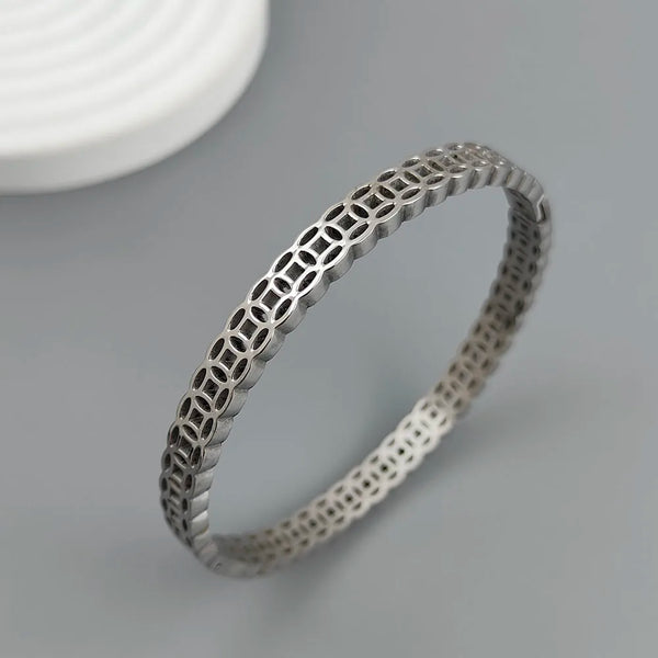 Silver bracelet with intricate design on a gray background